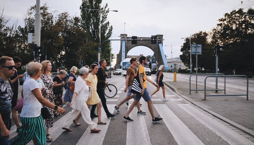Osiedle Plac Grunwaldzki. Ludzie na przejściu dla pieszych, w tle Most Grunwaldzki