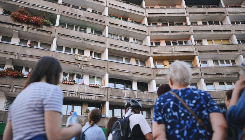 <p>Osiedle Plac Grunwaldzki. Grupka os&oacute;b stojąca pod blokiem</p>