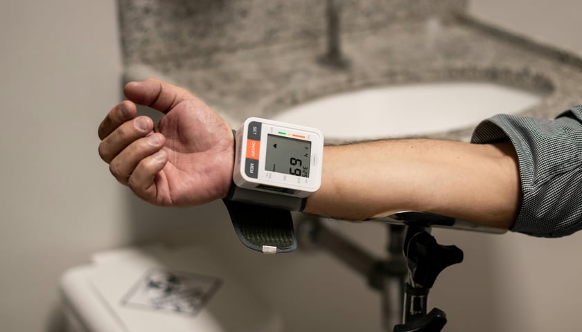 Ręka młodego dorosłego mężczyzny z założonym na nadgarstek ciśnieniomierzem