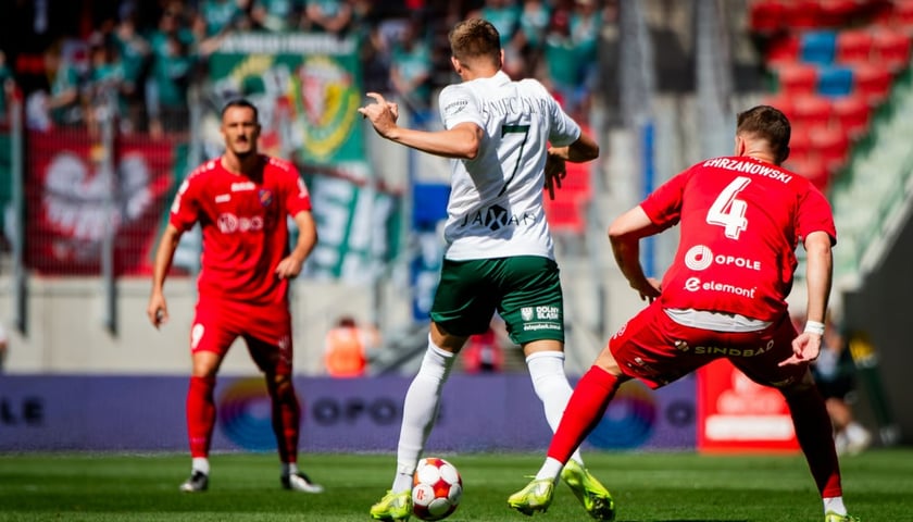 Zdjęcie ilustracyjne przedstawiające trzech piłkarzy na boisku w trakcie gry - mecz Śląsk Wrocław - Odra Opole.