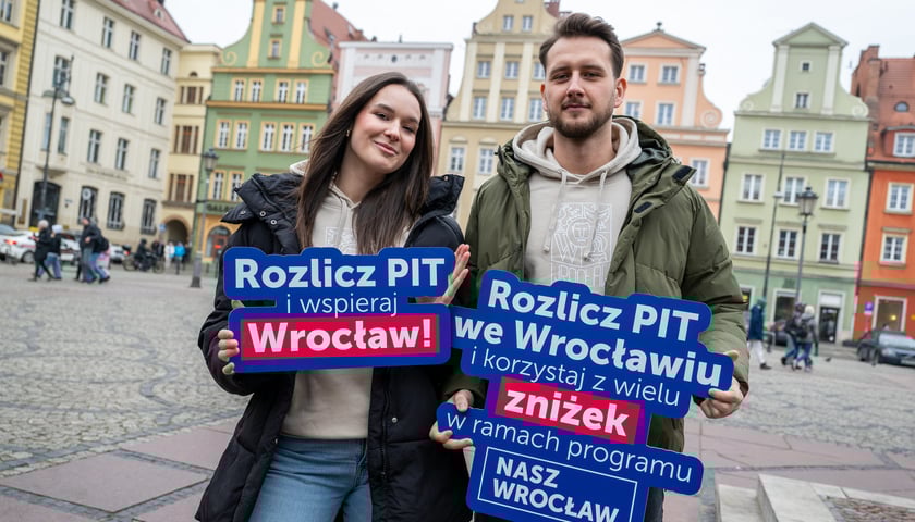 Chłopak i dziewczyna na wrocławskim rynku, trzymający napis "Rozlicz PIT we Wrocławiu"