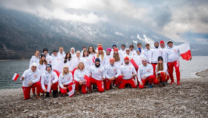 <p>Grupa sportowc&oacute;w w białych bluzach i czerwonych spodniach na tle ośnieżonych g&oacute;r - kadra Polski w pływaniu lodowym, Molveno 2026</p>