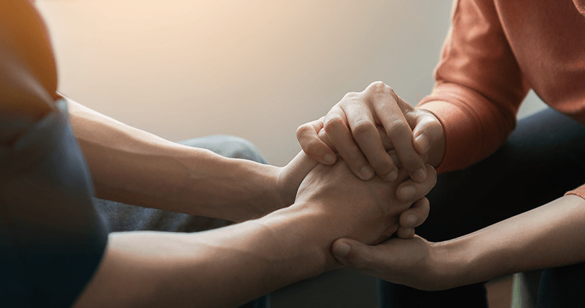 Na zdjęciu dwie osoby trzymające się za ręce. Zobacz, gdzie uzyskasz pomoc psychologiczną we Wrocławiu!