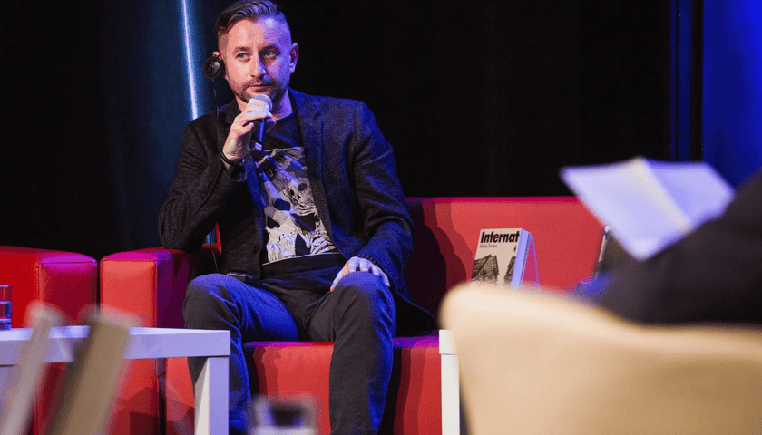 Serhij Żadan, ukraiński pisarz, poeta, eseista, muzyk i działacz społeczny, odbierze tytuł doktora honoris causa Uniwersytetu Wrocławskiego. Na zdjęciu mężczyzna przemawia do mikrofonu