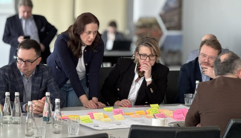 Warsztaty strategiczne Wrocławskiego Obszaru Metropolitalnego. Na zdjęciu grupa osób dyskutuje przy stole