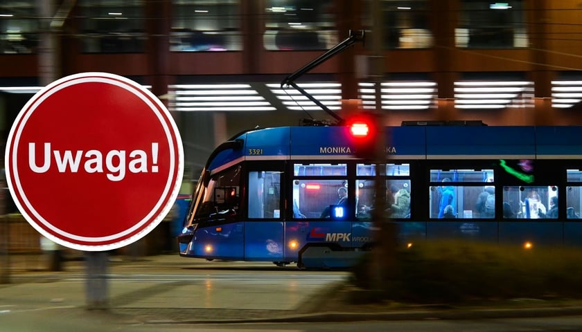 Zdjęcie ilustracyjne - tramwaj jadący wieczorem ulicą, w lewej części zdjęcia okrągłe, czerwone koło z białym napisem "Uwaga!" w środku.