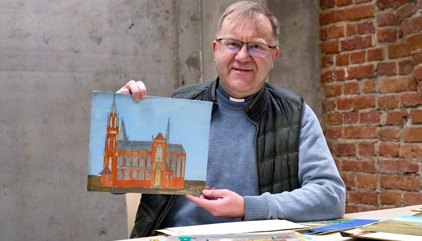 Ks. dr hab. Grzegorz Sokołowski z Archiwum Archidiecezjalnego prezentuje rysunek Anneliese. Na zdjęciu mężczyzna w okularach trzyma w dłoniach rysunek