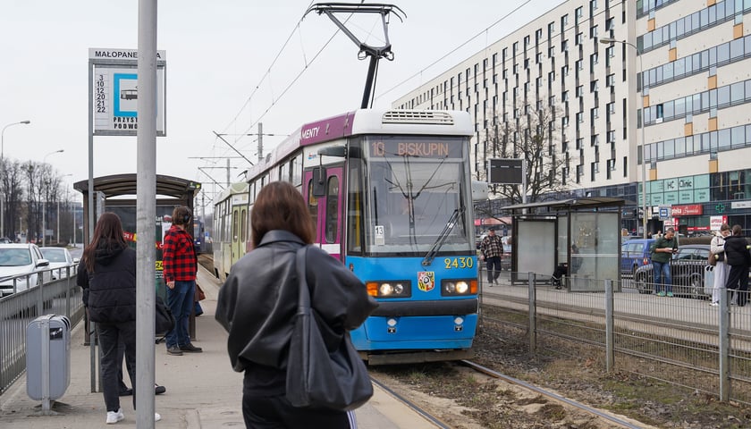 Ludzie stojący na przystanku "Małopanewska" i nadjeżdżający tramwaj po wznowieniu ruchu tramwajowego.