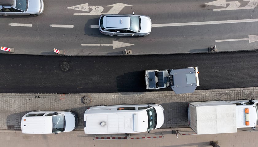 Układanie masy bitumicznej na ulicy Powstańców Śląskich między Orlą a Krzycką