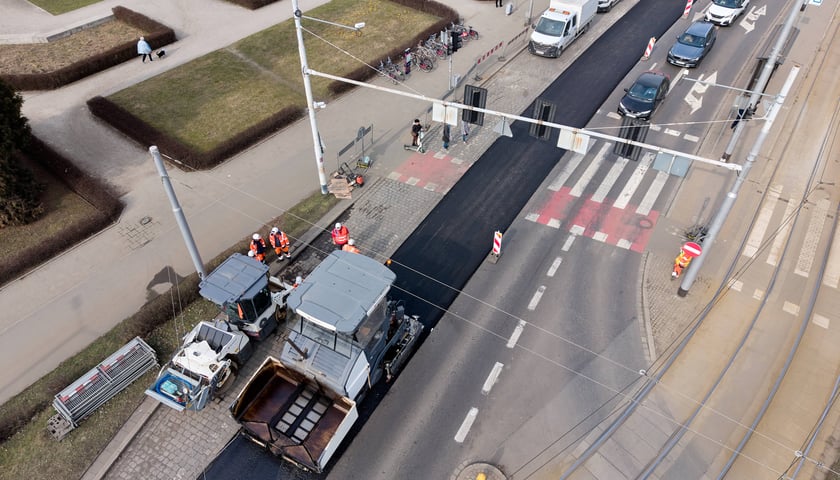 Układanie masy bitumicznej na ulicy Powstańców Śląskich między Orlą a Krzycką