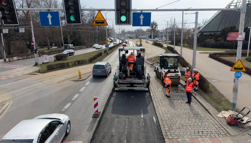 Układanie masy bitumicznej na ulicy Powstańców Śląskich między Orlą a Krzycką