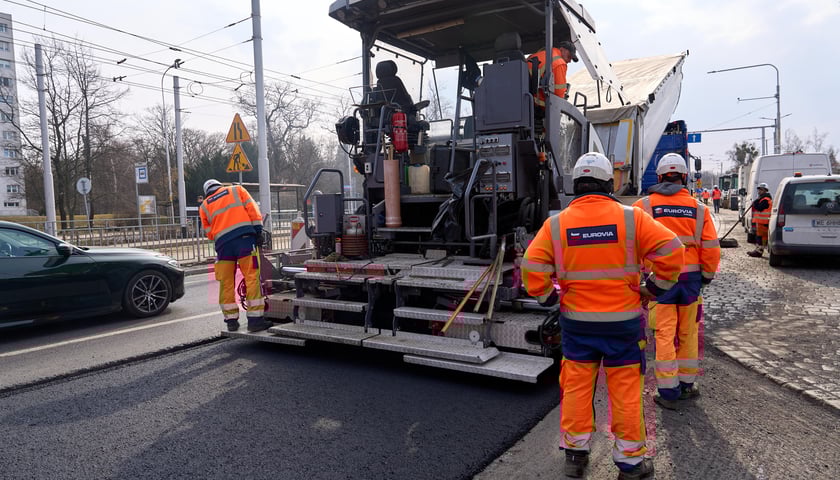 Układanie masy bitumicznej na ulicy Powstańców Śląskich między Orlą a Krzycką