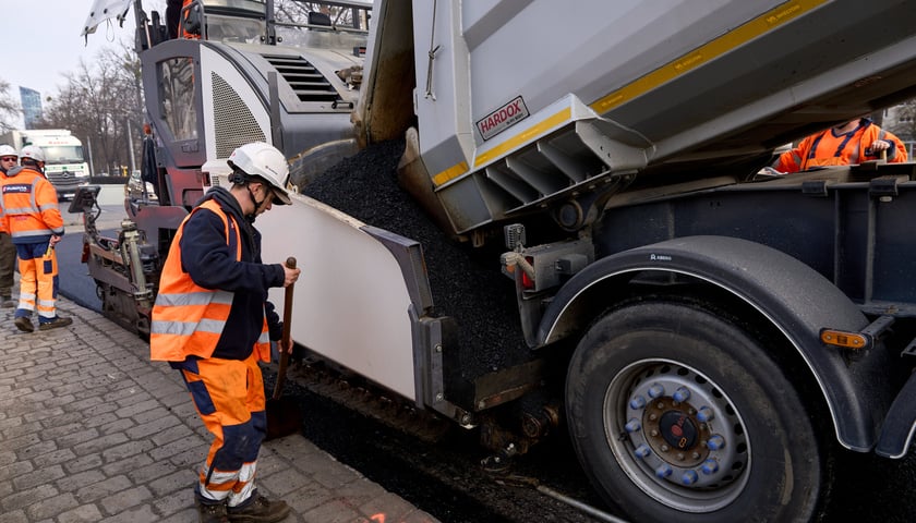 Układanie masy bitumicznej na ulicy Powstańców Śląskich między Orlą a Krzycką
