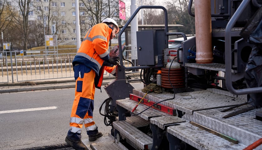 Układanie masy bitumicznej na ulicy Powstańców Śląskich między Orlą a Krzycką