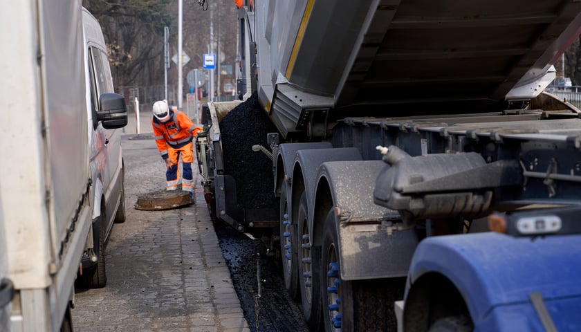 Układanie masy bitumicznej na ulicy Powstańców Śląskich między Orlą a Krzycką