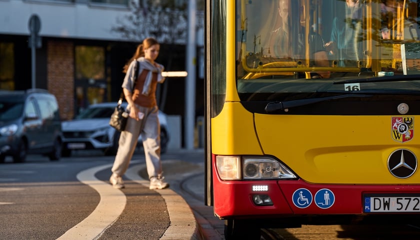 Na zdjęciu młoda kobieta wsiada do autobusu miejskiego. Zdjęcie ilustracyjne