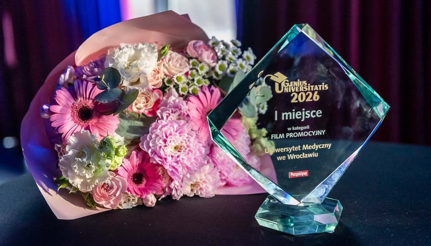Statuetka nagrody Genius Universitatis dla Uniwersytetu Medycznego we Wrocławiu, obok bukiet kwiatów