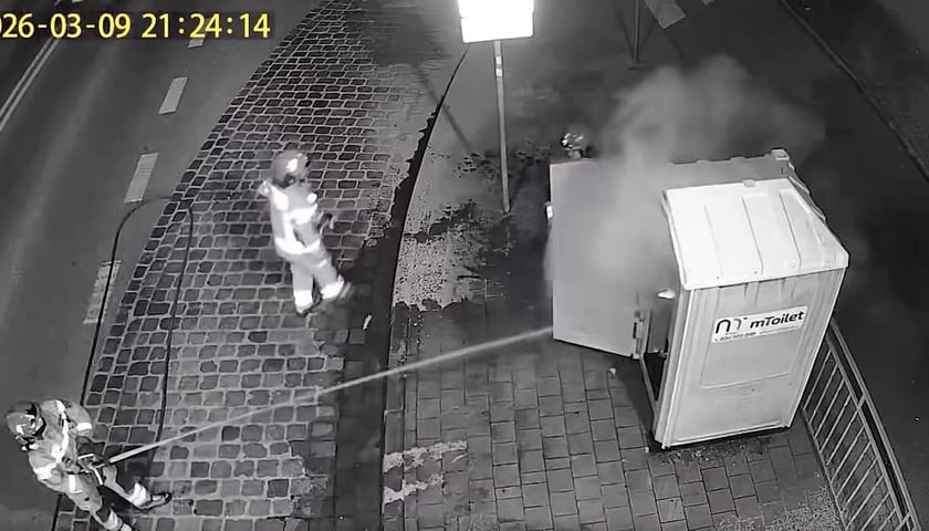 Stop klatka z monitoringu - strażacy gaszą pożar przenośnej toalety