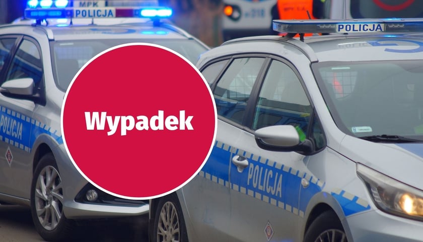 W tle: pojazdy policji, w kółku: napis ''wypadek''