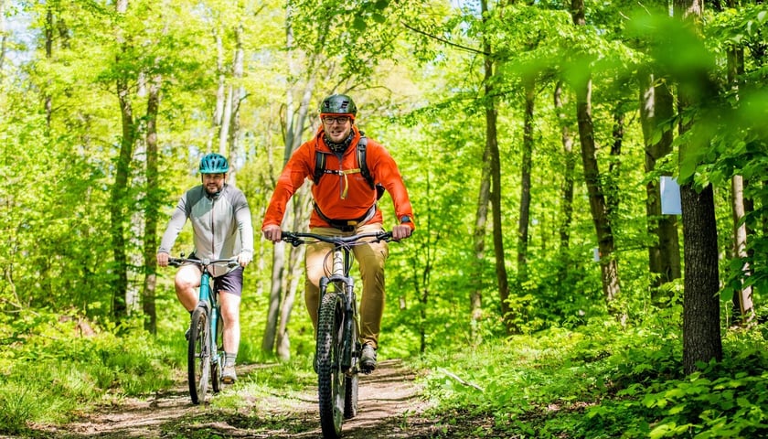 Sportowcy na trasie Maratonu Rowerowego w Henrykowie. Na zdjęciu dwóch mężczyzn na rowerach jedzie przez las