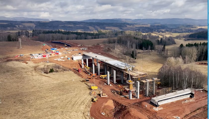 Kadr  filmu z budowy autostrady D11. Na zdjeciu z lotu ptaka widać budowę mostu