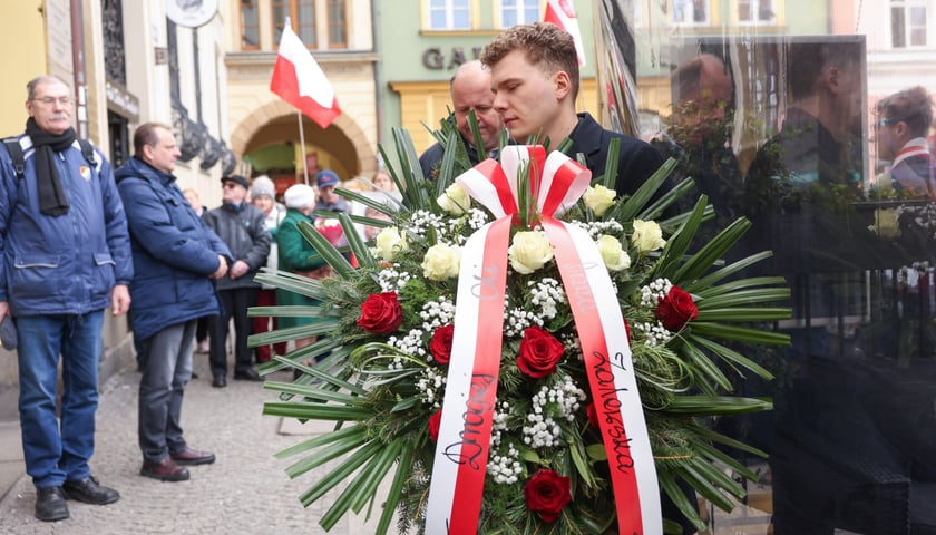 Składanie kwiat&oacute;w pod tablicą Aleksandry Natalii-Świat