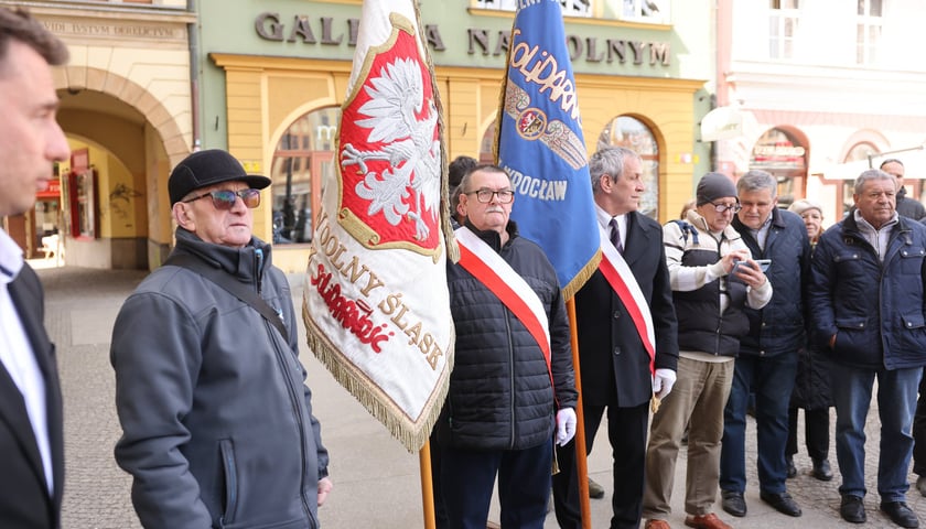 Składanie kwiat&oacute;w pod tablicą Aleksandry Natalii-Świat