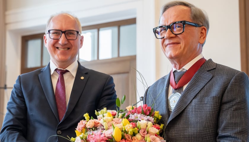 Na zdjęciu obok siebie stoi dwóch uśmiechniętych mężczyzn. Po lewej rektor Politechniki Wrocławskiej, prof. Arkadiusz Wójs, po prawej uhonorowany medalem Grzegorz Dzik
