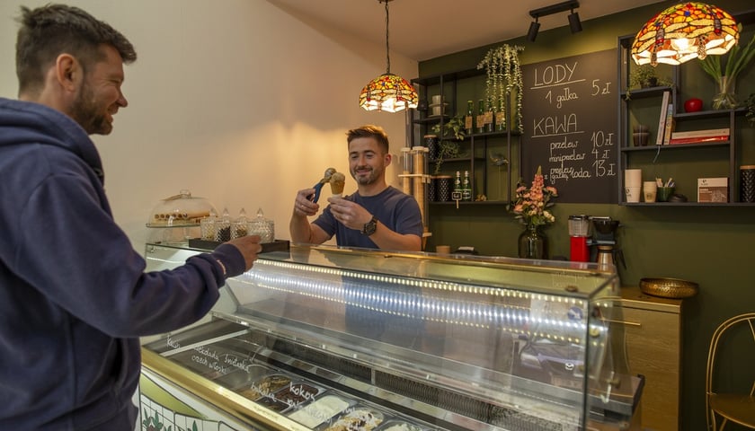 Powiększ obraz: - Polecam malinowe, wegańskie lody typu sorbet i wiele innych smaków i rodzajów lodów - mówi Paweł Jakubowski, właściciel lodziarni Cybulskiego 10 i nakłada gałkę lodów o smaku prażonych orzechów włoskich.