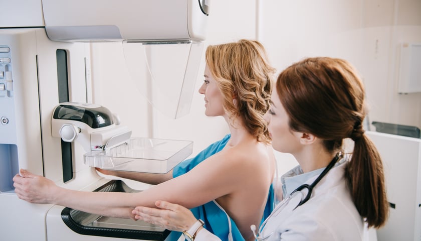 Powiększ obraz: Na zdjęciu kobieta w czasie badania mammografem
