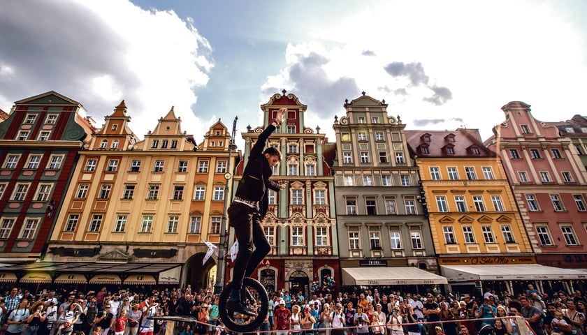 Powiększ obraz: Mężczyzna na monocyklu jadący na linie rozpiętej na wrocławskim Rynku