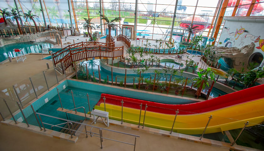 Powiększ obraz: Na zdjęciu kolorowe wnętrze aquaparku przy ul. Borowskiej: żółta i czerwona zjeżdżalnia, niebieska leniwa rzeka