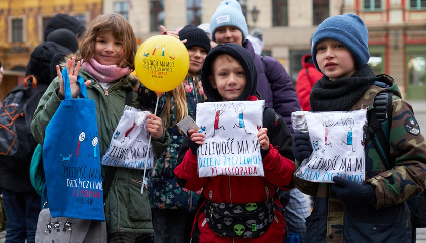 Powiększ obraz: Na zdjęciu uśmiechnięte dzieci z gadżetami (płócienna torba, zapakowane koszulki, balonik) związanymi z Dniem Życzliwości