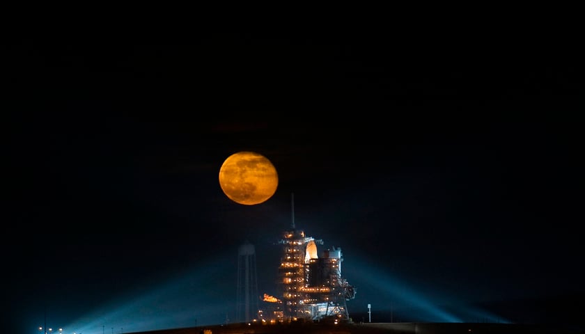 Powiększ obraz: Na zdjęciu Księżyc górujący nad startującym promem kosmicznym.