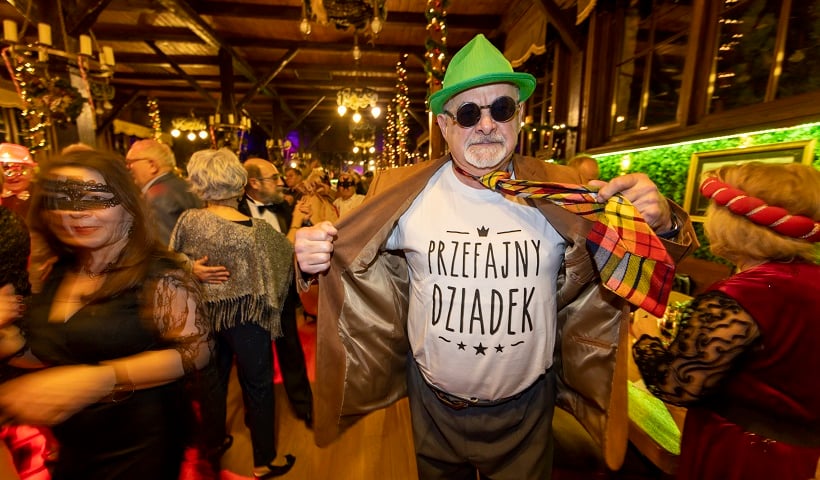 Powiększ obraz: Na zdjęciu senior w zielonym kapeluszu, ciemnych okularach i koszulce z napisem "Przefajny dziadek"