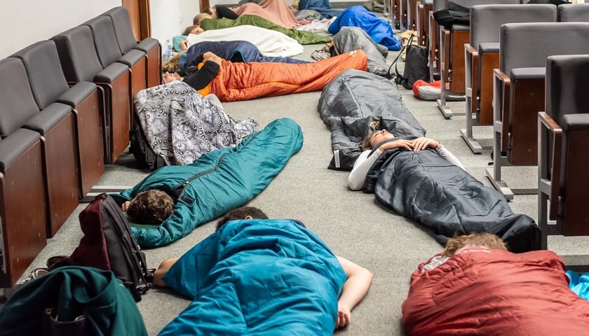 Powiększ obraz: Na zdjęciu leżący w śpiworach na podłodze w sali wykładowej studenci Uniwersytetu Medycznego w Wrocławiu