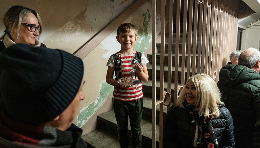 Powiększ obraz: Na zdjęciu chłopiec  z miseczką z cukierkami na spotkaniu reporterki z mieszkańcami Trzonolinowca