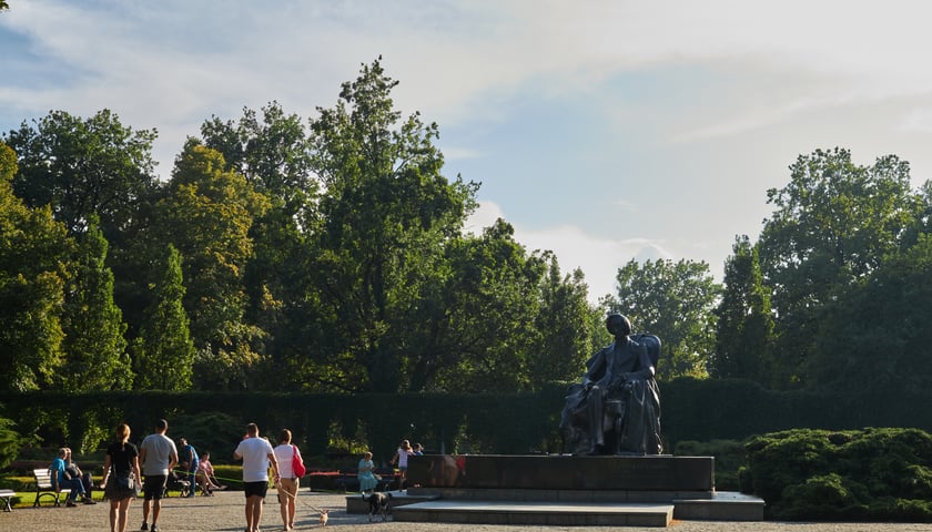 Powiększ obraz: <p>Na zdjęciu ludzie spacerujący po parku Południowym we Wrocławiu. Po prawej znajduje się pomnik Chopina.</p>
