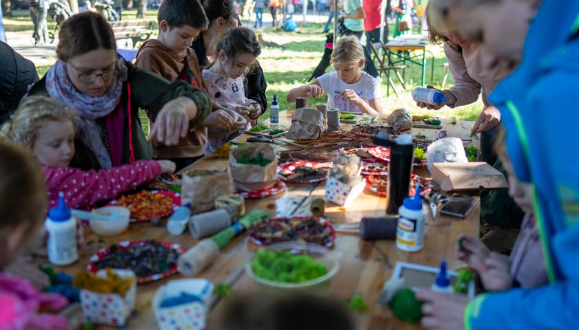 Powiększ obraz: Dzieci przy stole podczas warsztatów plenerowych - jesienna edycja WROśnij we Wro w parku Zachodnim