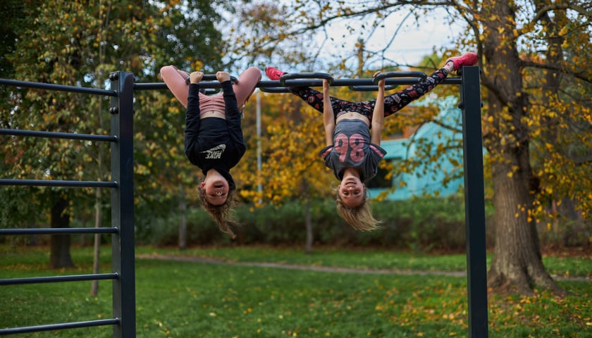 Powiększ obraz: Na zdjęciu dzieci ćwiczące w Parku Klecińskim. Siłownie plenerowe są bezpłatne i dostępne dla wszystkich mieszkańców.