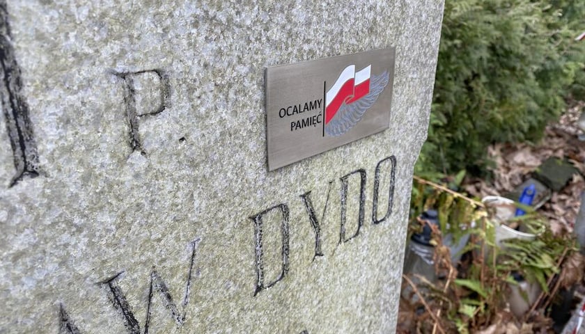 Powiększ obraz: granitowy nagrobek z metalową tabliczką o treści "ocalmy pamięć" - cmentarz Osobowicki we Wrocławiu