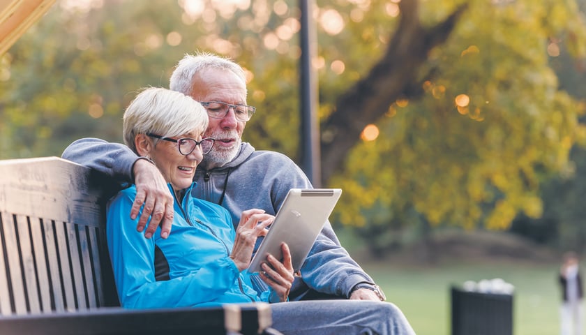 Powiększ obraz: Para seniorów z tabletem na ławce