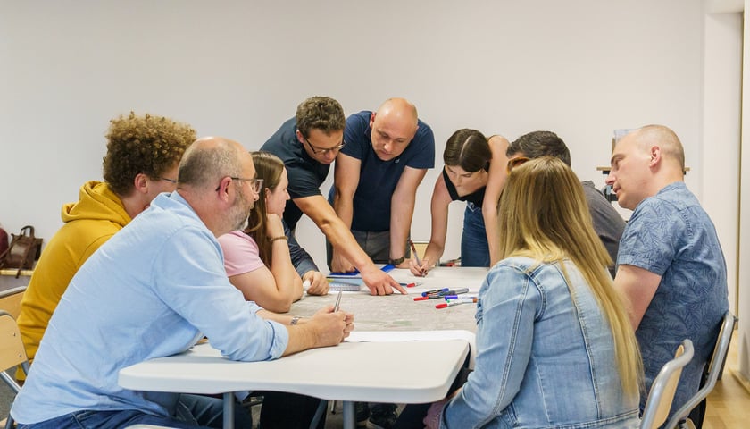 Powiększ obraz: Mieszkańcy Ołtaszyna, Wojszyc i Jagodna podczas konsultacji ws. odkorkowania południa Wrocławia pochyleni nad mapą, maj 2024