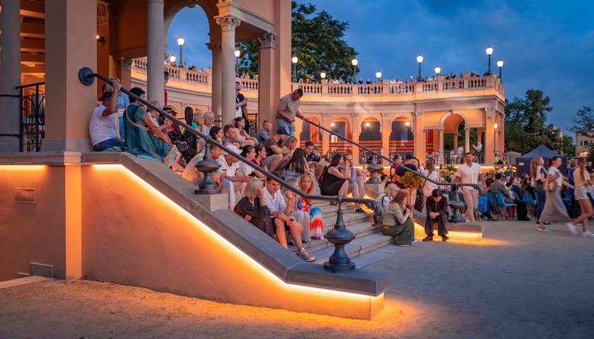 Powiększ obraz: Wieczór na Bastionie Sakwowym - ludzie siedzący na schodach podczas koncertu