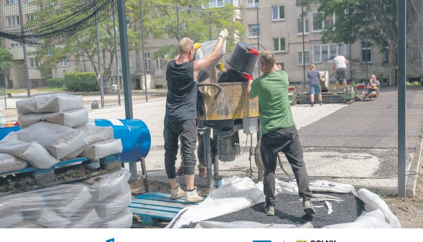 Powiększ obraz: Dwaj mężczyźni pracujący przy remoncie wnętrza podwórzowego