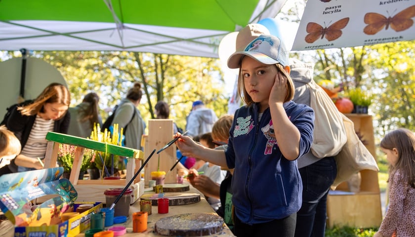 Powiększ obraz: Dziewczynka w czapce z daszkiem z pędzlem w ręce podczas zeszłorocznej edycji Soboty z Zielonym Wrocławiem