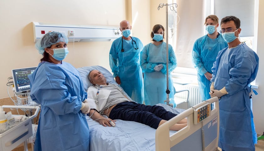 Lekarze stoją wokół łózka pacjenta w szpitalu. Jan Kowalski podczas terapii CAR-T w Klinice Hematologii UMW.