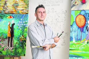 Powiększ obraz: Rysownik grafik na Dzień Życzliwości Andrzej Tylkowski - z pędzlami na tle swoich prac