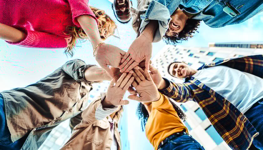 Powiększ obraz: Grupa ludzi przybijająca piątkę