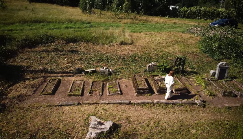 Powiększ obraz: Kadr z filmu "Opiekunowie (nie)pamięci” . Na zdjęciu widok rzędu nagrobków z lotu ptaka